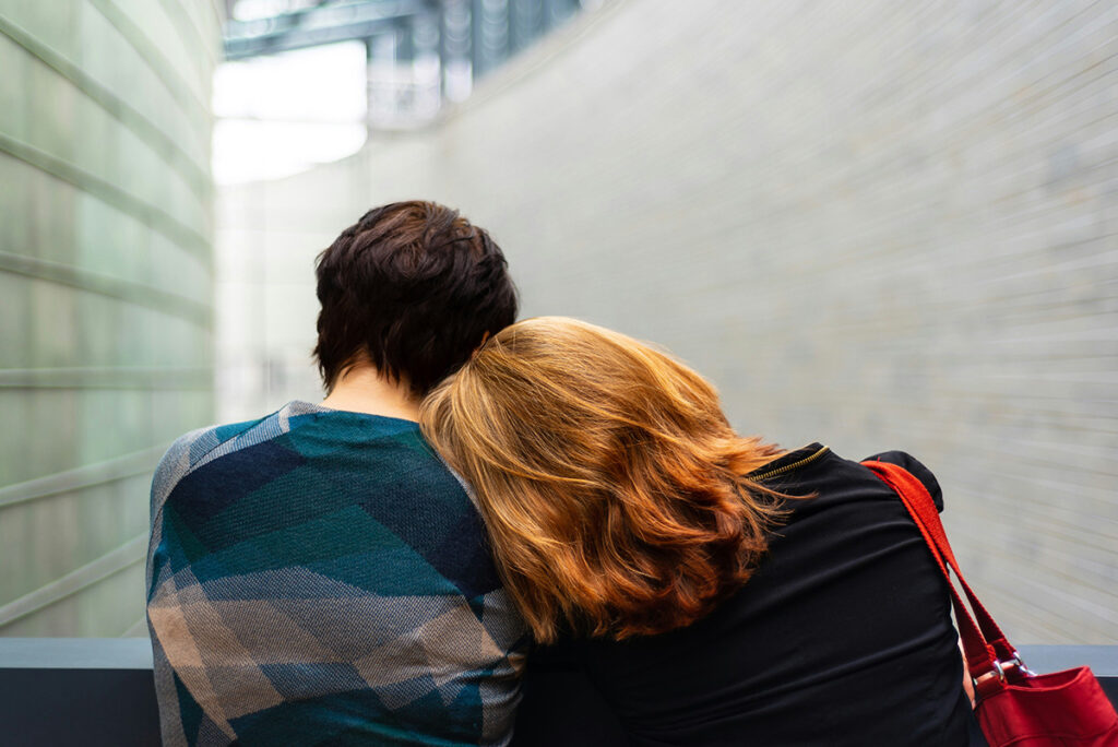 A woman rests her head on another person's shoulder