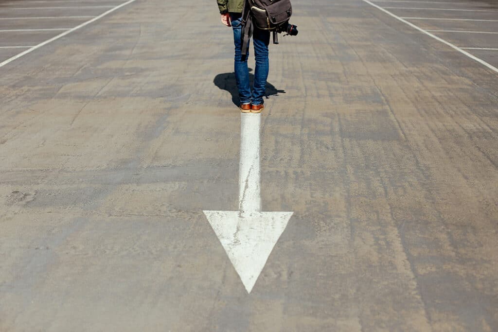 A person standing on an arrow sign, facing the opposite direction