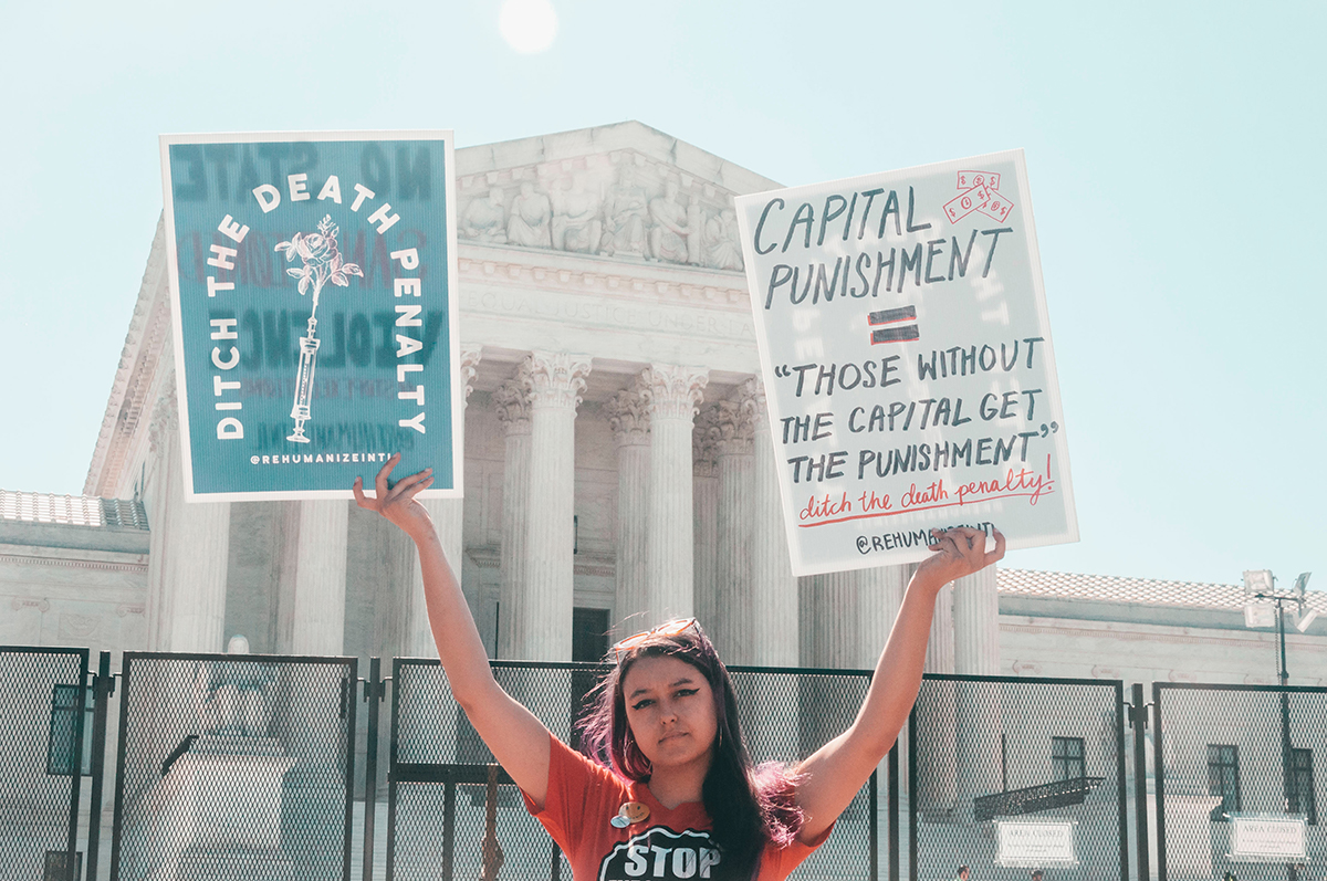 An activist holds signs protesting the death penalty in front of the US Supreme Court in Washington, D.C.