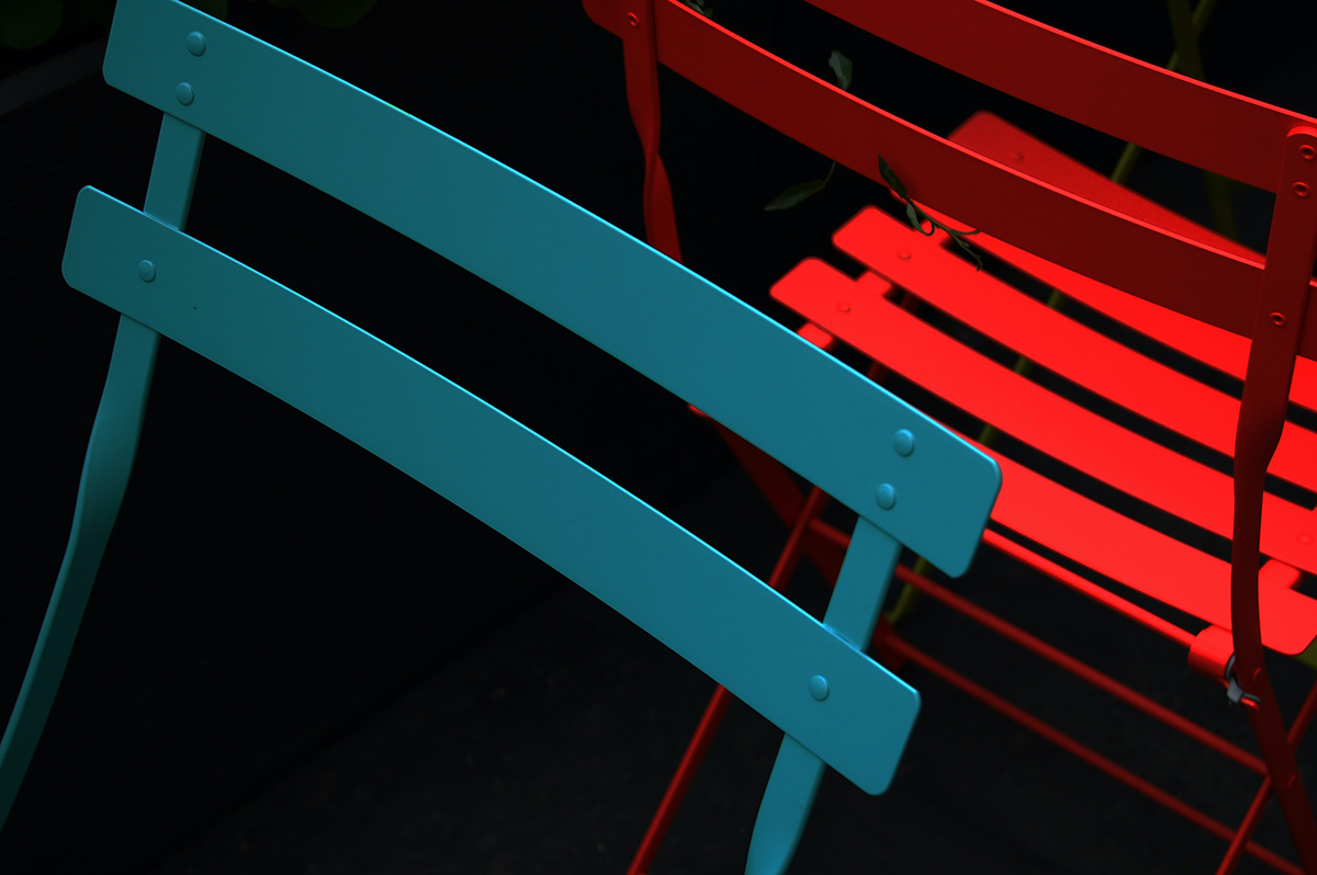 A pair of blue and red chairs sit facing away from each other.
