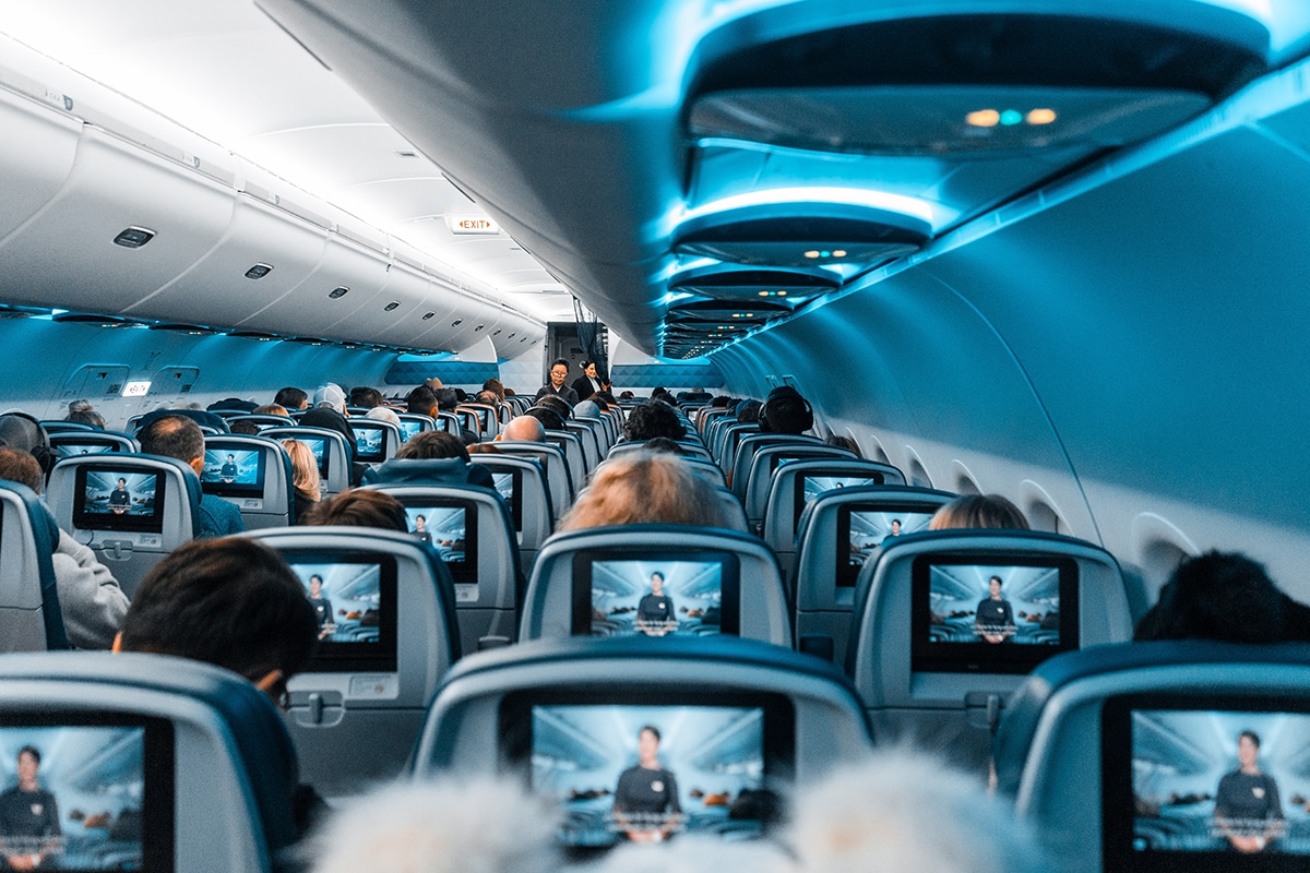 Passengers on an airplane watch a pref-flight safety video