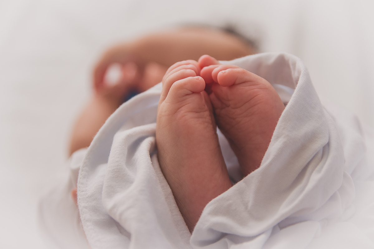 A baby wrapped in a blanket with its feet sticking out