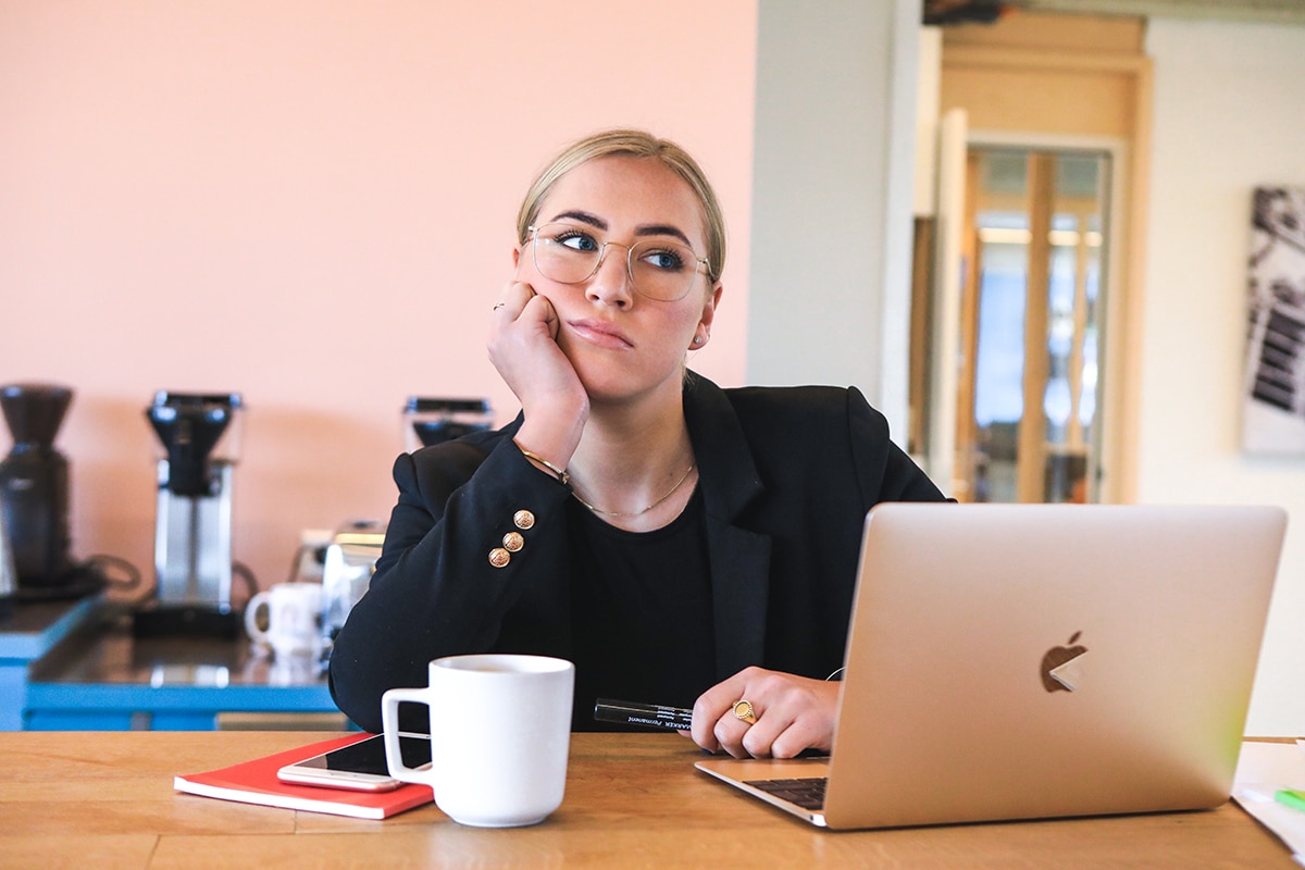 A Gen Z office worker sits at her desk bored and frustrated