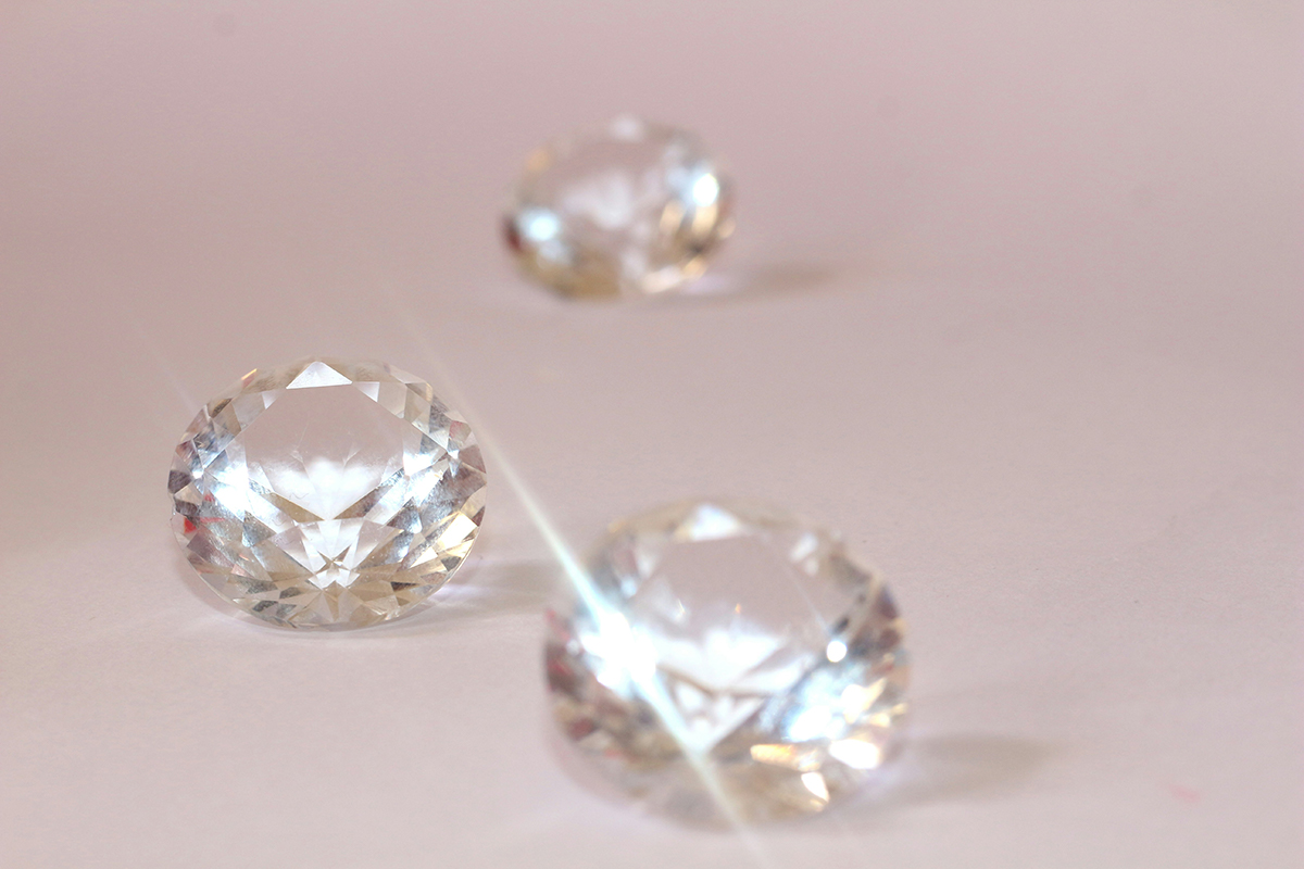 A close-up image of several diamonds on a pink background