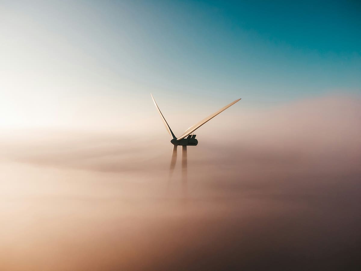 A wind turbine spins in a cloud of mist