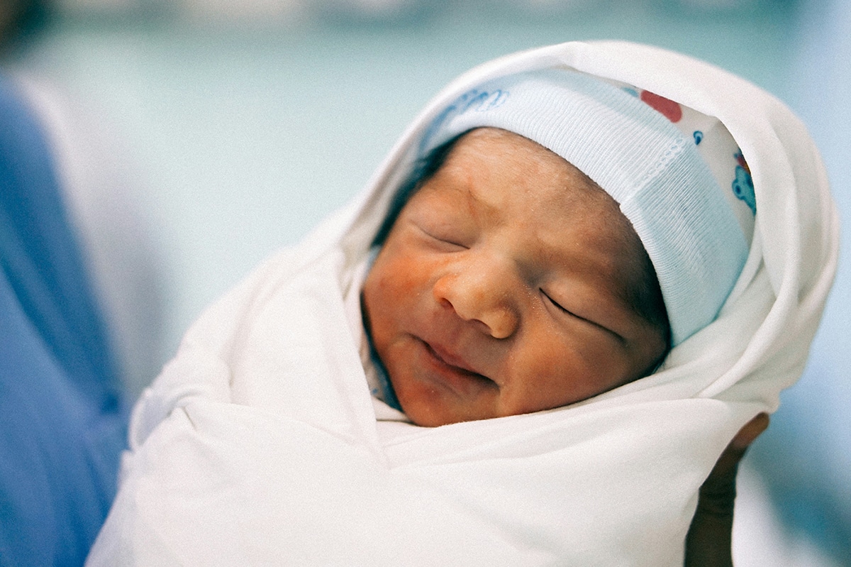 Photo of a healthy newborn baby wrapped in a blanket in a hospital