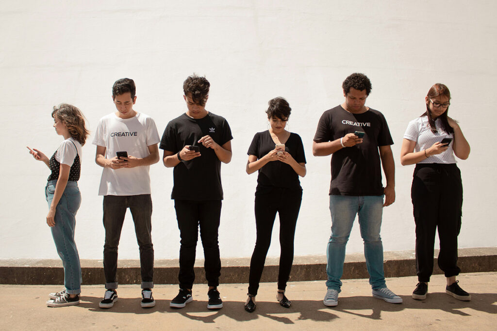 Gen Z teens standing around and looking at their phones