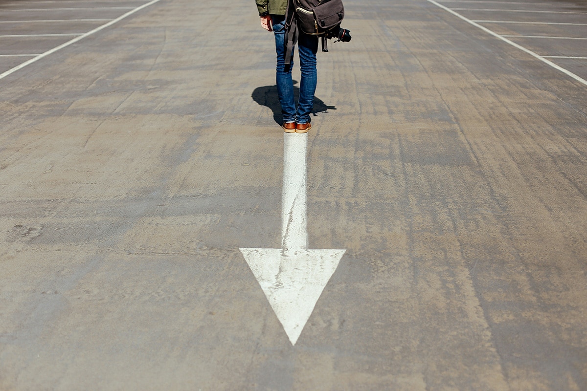 A person standing on an arrow sign, facing the opposite direction